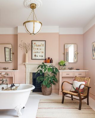 Bathroom with freestanding bath in the centre of the room with a soft pink paint color on the walls