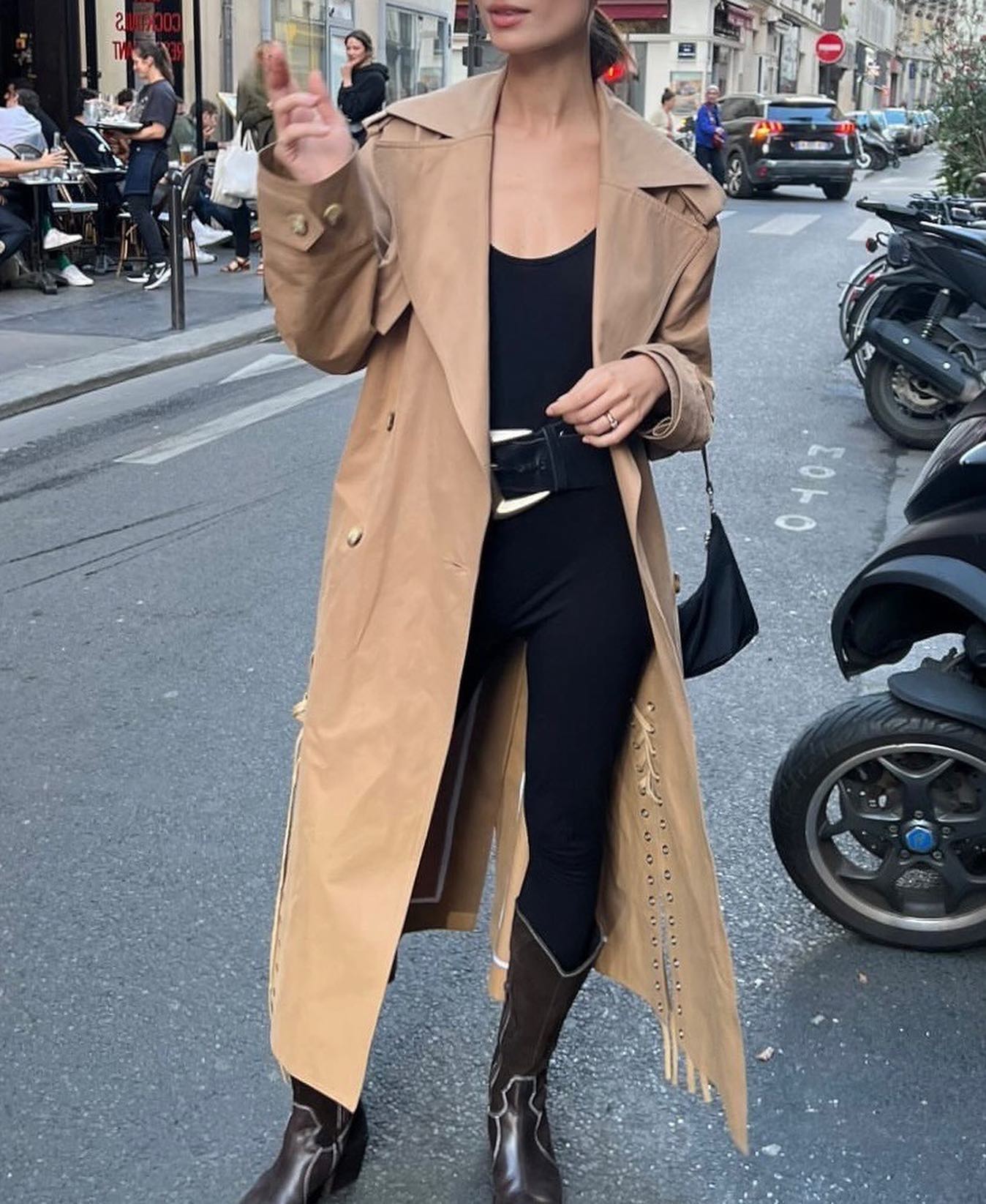 Andrea Ricci wears a trench coat, tank top and leggings tucked into cowboy boots.