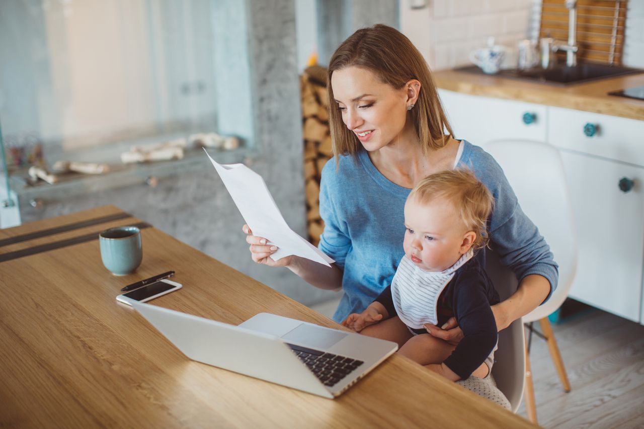 Mum holding paper at laptop