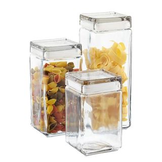 Three square glass containers with lids hold pasta
