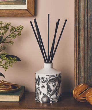 A black and white reed diffuser on a wooden table