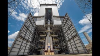 a white rocket stands inside an assembly building