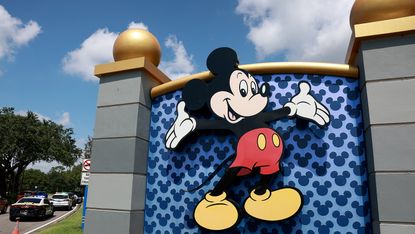 A sign at the entryway to Disney World with Mickey Mouse on it.