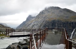 A viewing platform surrounded by mountains under a cloudy sky
