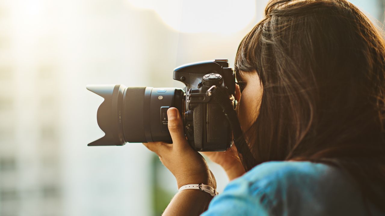 A woman taking a picture with one of the best DSLRs