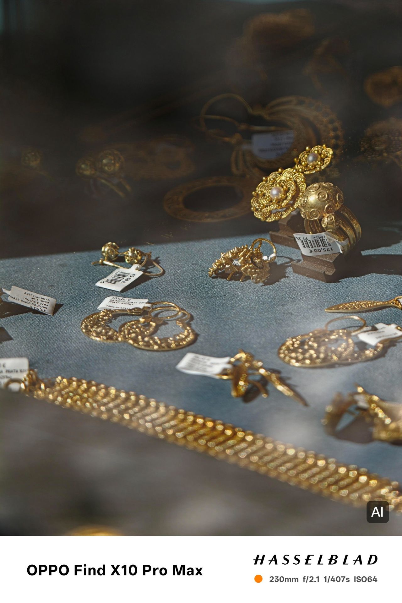 Gold jewelry and pearl earrings displayed behind glass with reflections across the window.