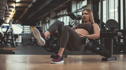 A woman performing a dumbbell hip thrust as part of a glute workout 