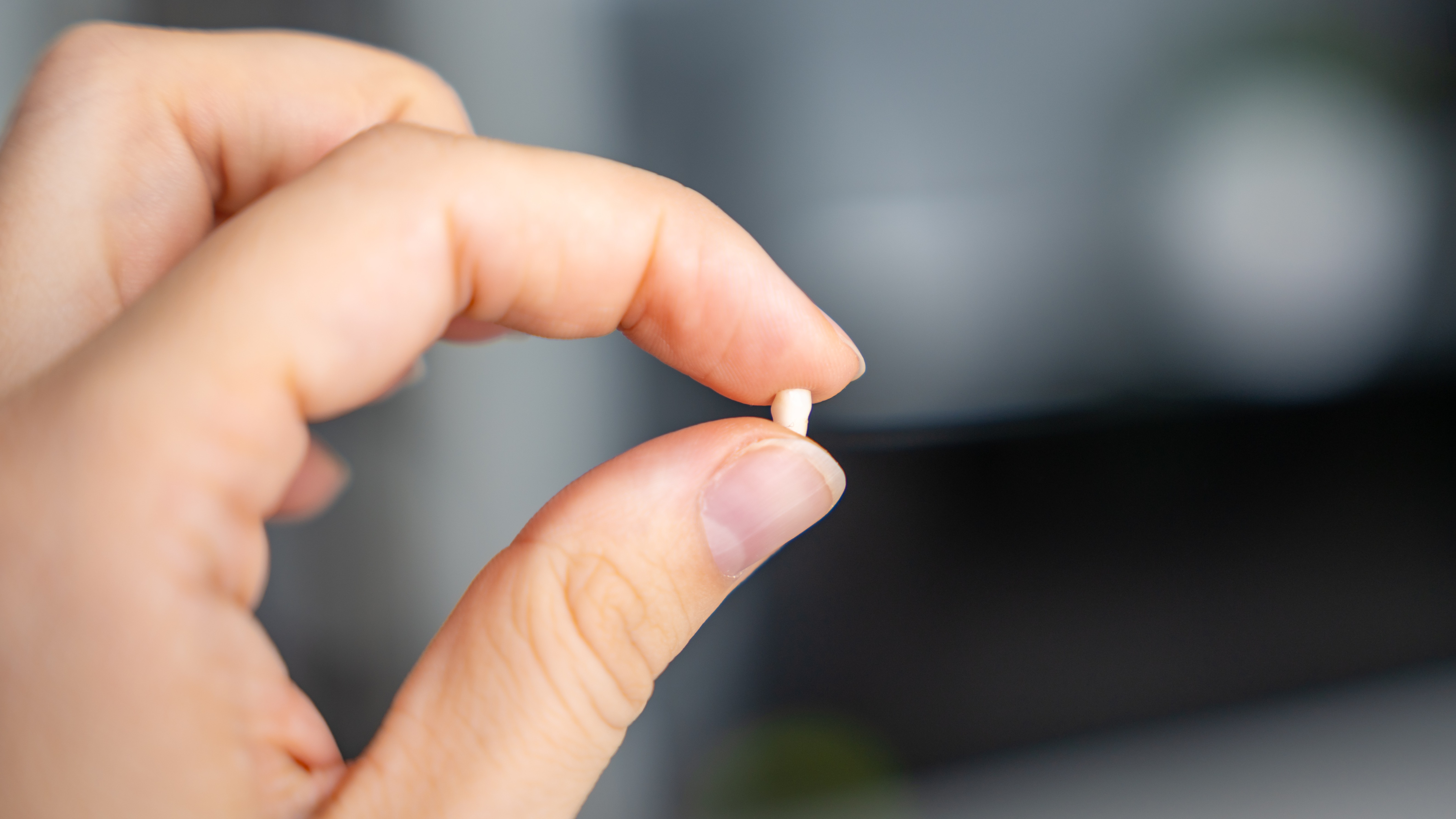 adult hand holding a baby tooth between the pointer finger and thumb