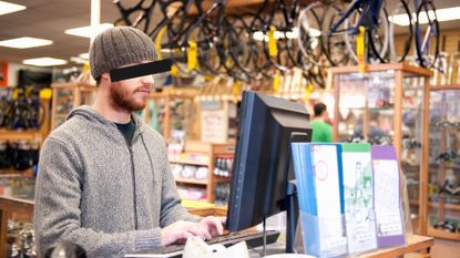 Image of bike shop owner at till with eyes covered
