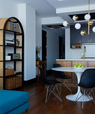 modern kitchen-dining room with black wall cabinets, wooden lower cabinets, dark wood flooring and modern black dining chairs around white round table