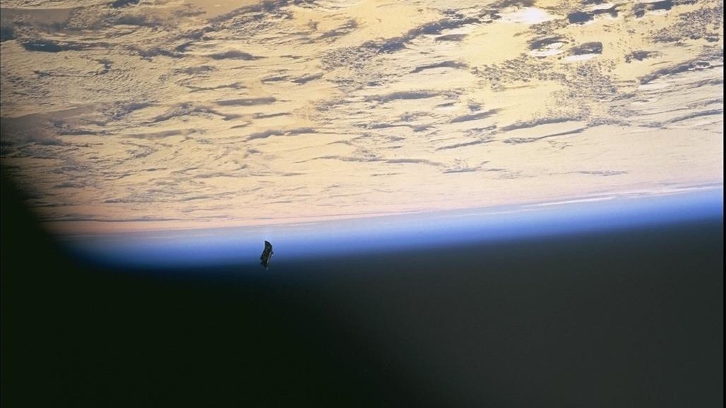 images captured from space show earth covered in clouds below and a small black object visible towards the left of the image.
