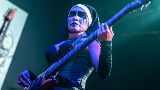 Nixe, bassist of heavy metal band Dogma, performing in a nun outfit and black-and-white face paint in 2025