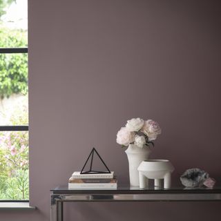 Wall painted in Benjamin Moore's Cinnamon Slate with a mirrored console table topped with white ceramics