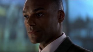 Colin Salmon stands smartly in the briefing room in Tomorrow Never Dies.