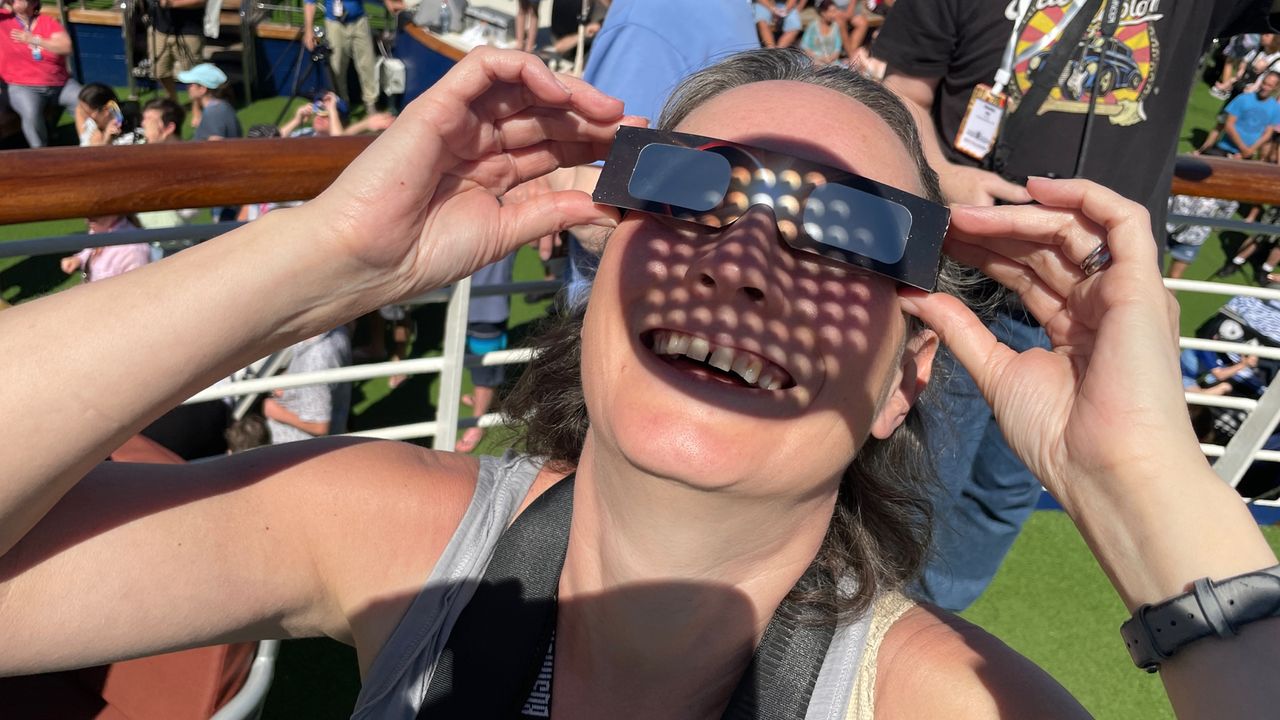 A woman gazes upward with special solar eclipse glasses.