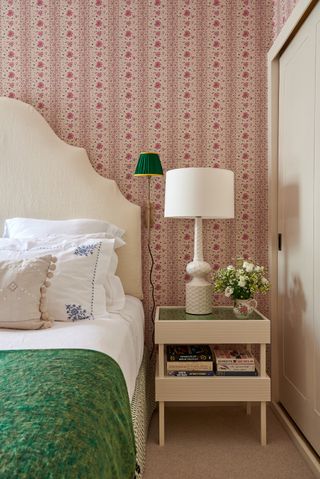 bedroom with pink floral wallpaper in a stripe, retro bedside, curved headboard, green blanket