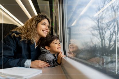 A mother and son sat on a train and looking out the window