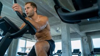 Does bike riding work your abs? Image shows: Man riding exercise bike in the gym