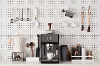 A kitchen with a pegboard holding mugs and utensils