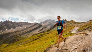An ultra runner in the Ultra tour du Mont Blanc descend the Grand Col Ferret into Switzerland