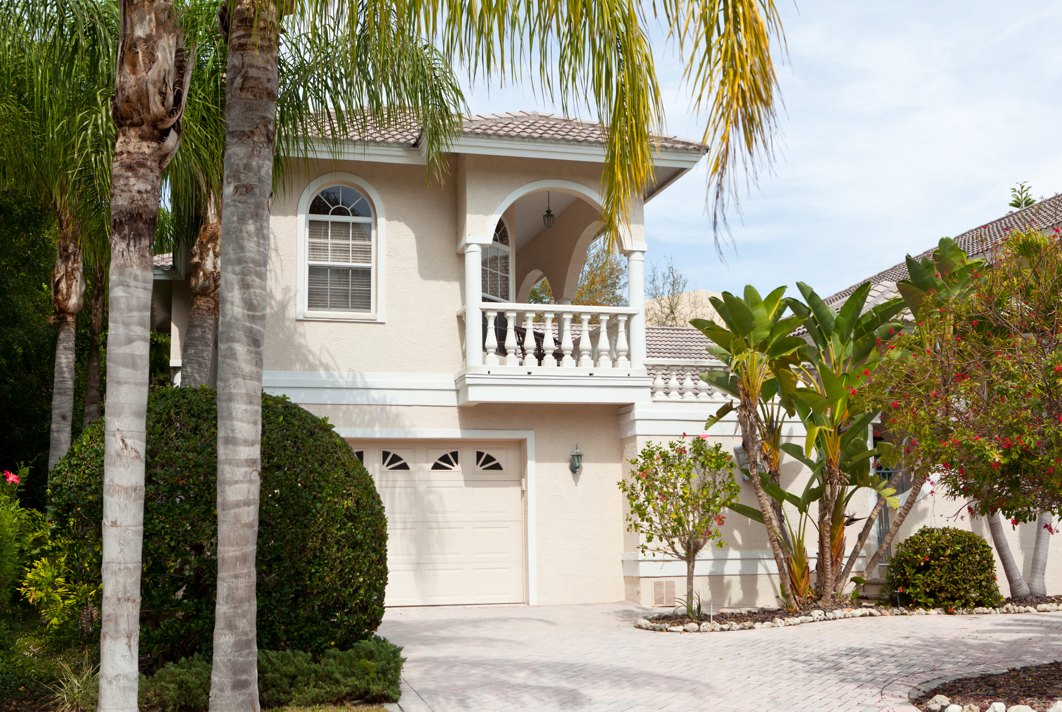light tan Florida villa with palm trees and foliage