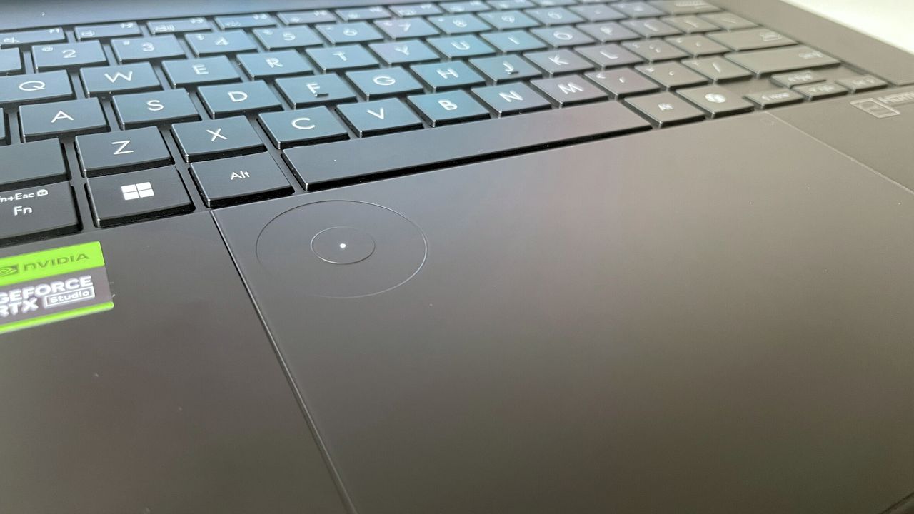 Close up of laptop's trackpad with a circular indentation at the top-left corner.