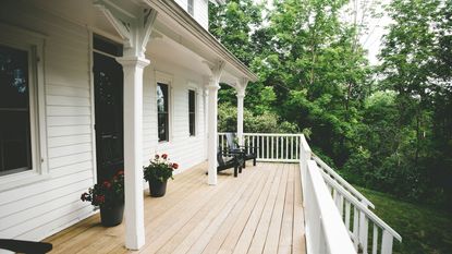 Front porch with light wood deck, small planters and white deck railing on modern home