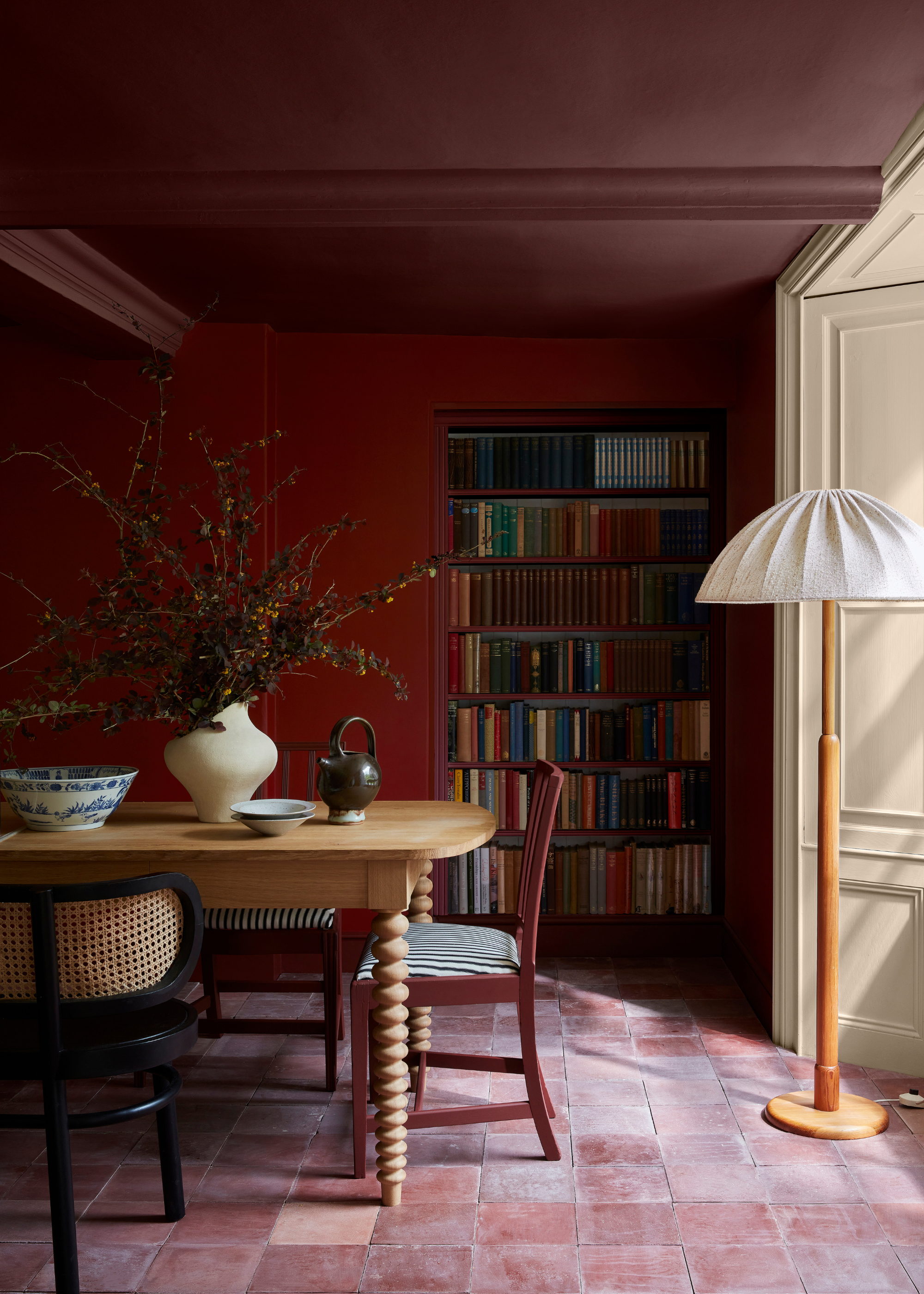 Red drawing room with bookcase and tall lamp