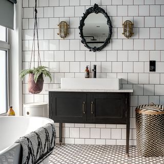 monochrome bathroom with white basin in black cabinet and black framed wall mirror