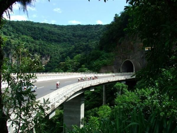 The yellow jersey group crosses a bridge high in the mountains