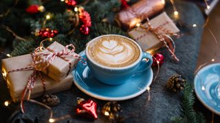 A cappuccino in a blue cup amongst presents and ornaments