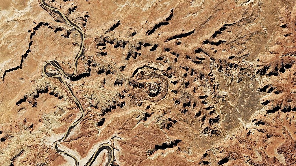 Satellite image of Upheaval Dome in Utah. We see a structure with concentric circles of rock surrounded by barren relief.