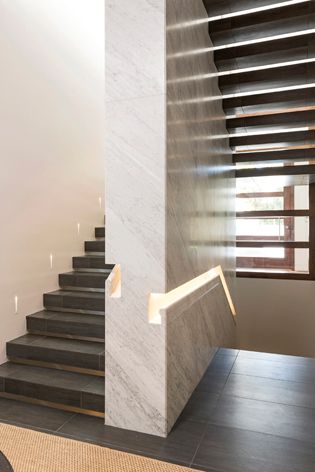 A marble-clad stairwell is lined with customised recessed lighting