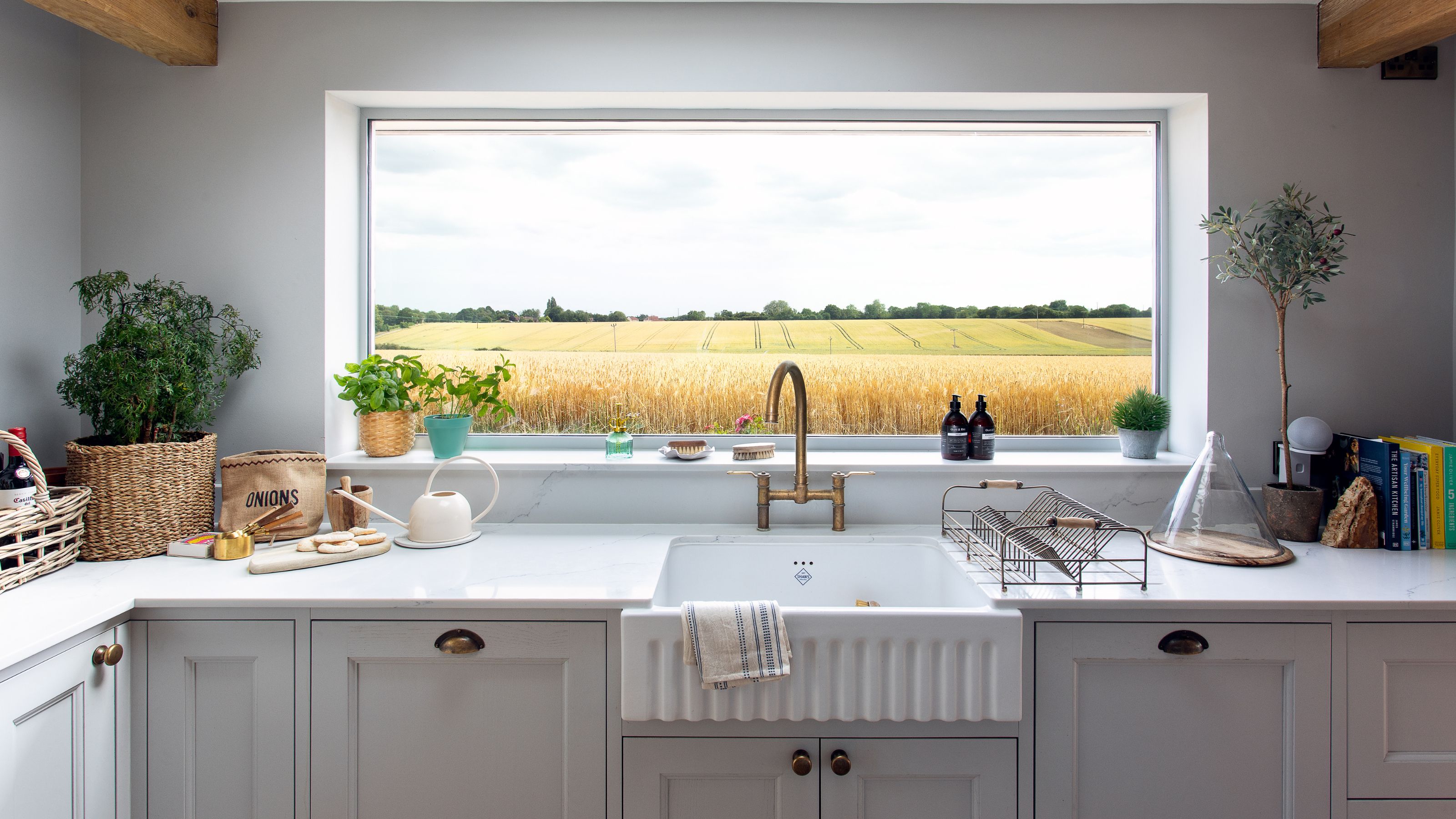 Kitchen sink area with a large picture window looking out onto fields with yellow plants in it