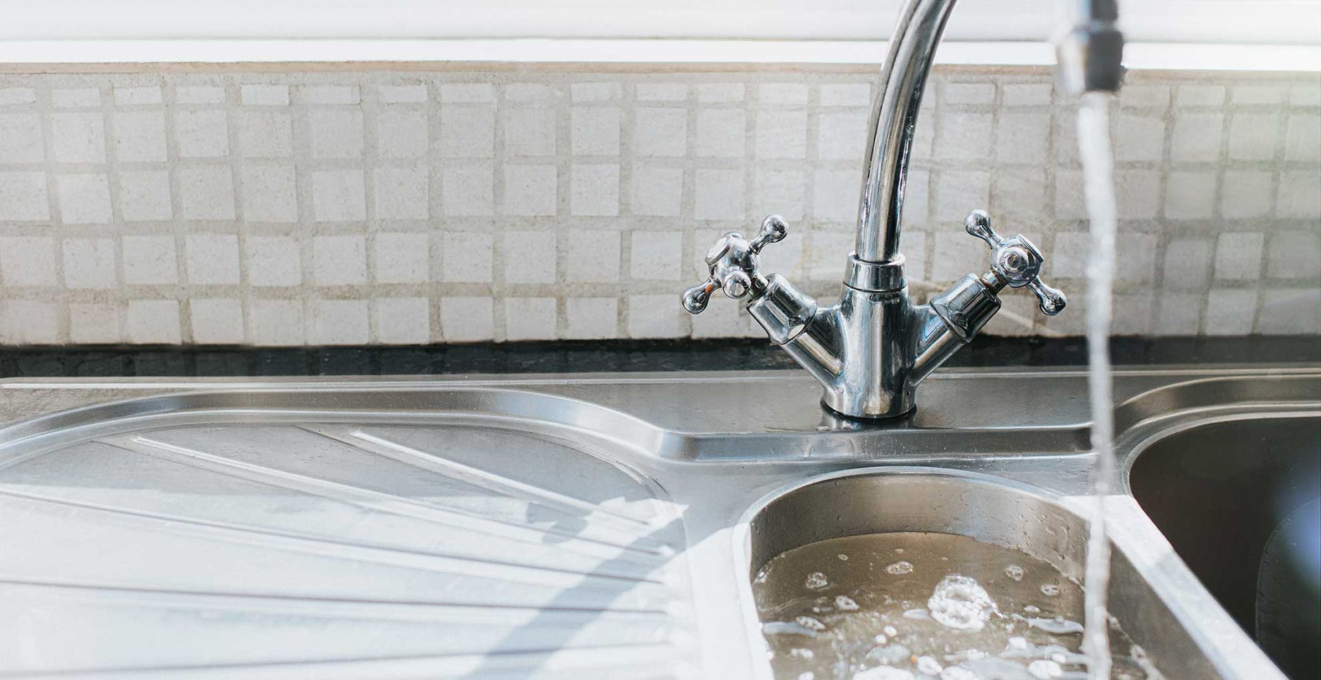chrome kitchen sink filled with water to show what to avoid to stop daddy long-legs coming in your house