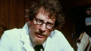 A bearded man in a lab coat and glasses looking at the camera in Faces of Death