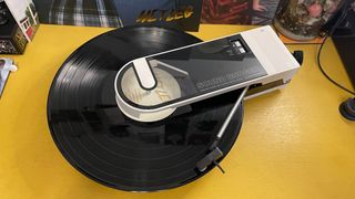 Audio Technica Sound Burger turntable with record spinning on yellow desk