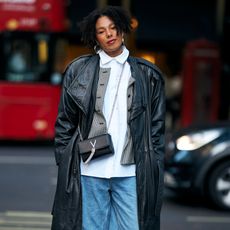 woman wearing a leather jacket, a white button-down, and jeans 