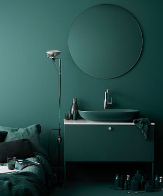 A dark teal bathroom with matching sink and vanity unit shows the colorful bathroom trend.