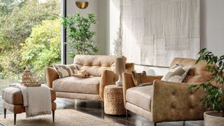 neutral living room with upholstered armchairs with button-back sustainable fabrics surrounded by houseplants to support key living trends 2023