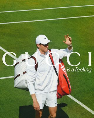 Gucci campaign starring Jannik Sinner on tennis court waving in tennis whites with Gucci holdall, over the image reads ’Gucci is a feeling’