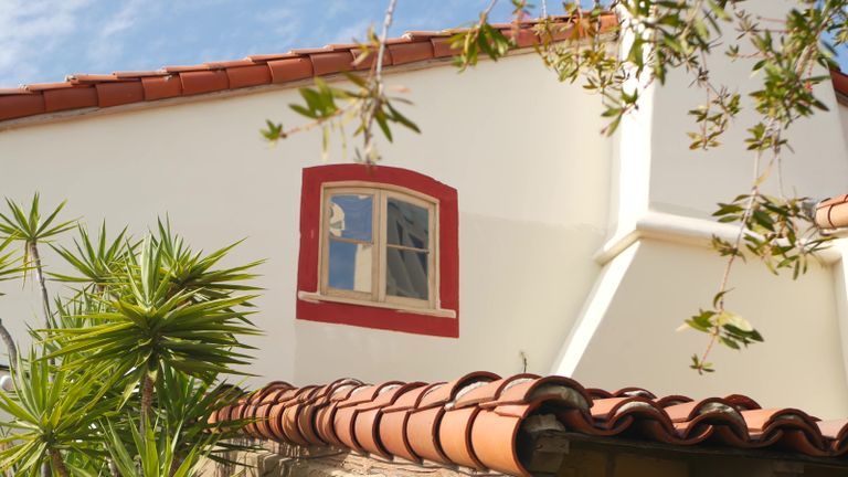Mexican colonial style suburban, hispanic house exterior, green lush garden, San Diego, California USA. Mediterranean terracotta ceramic clay tile on roof