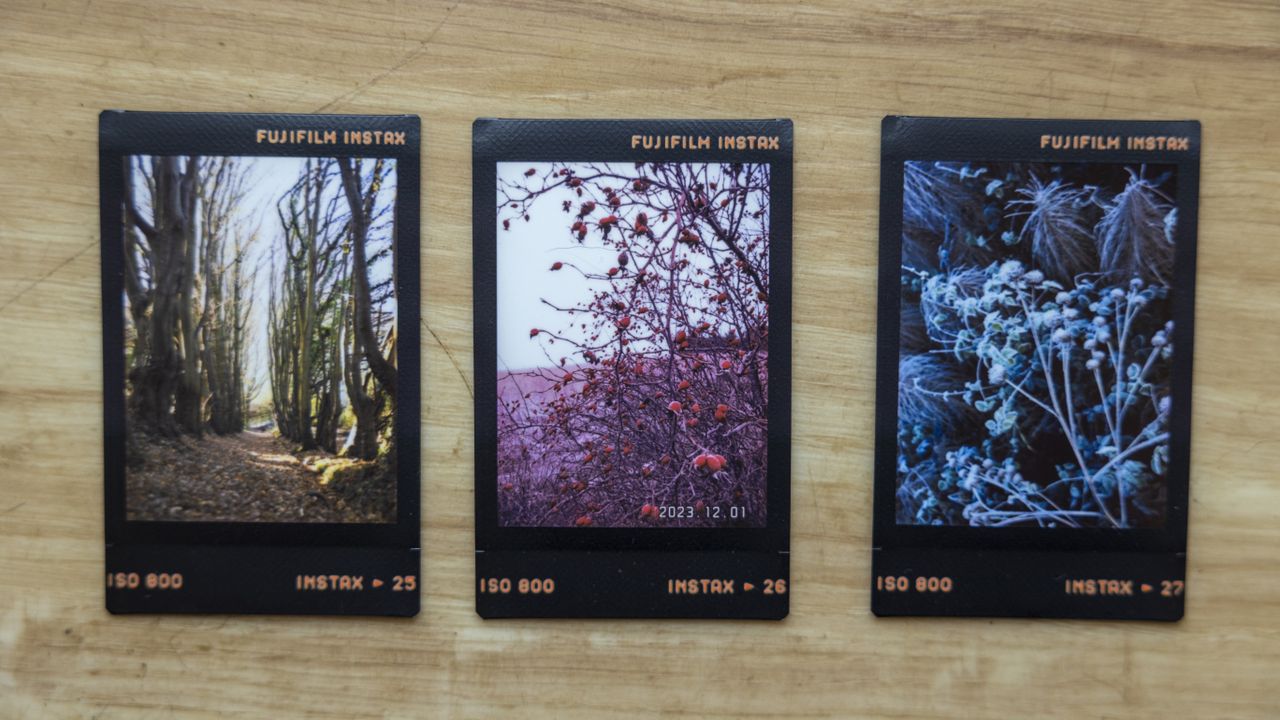Three Instax prints with a black frame on a wooden floor