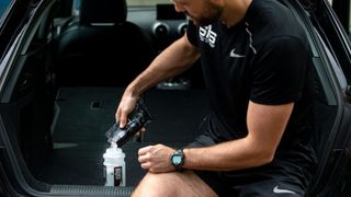 Man purs SiS Beta Fuel into a water bottle to make a sports drink