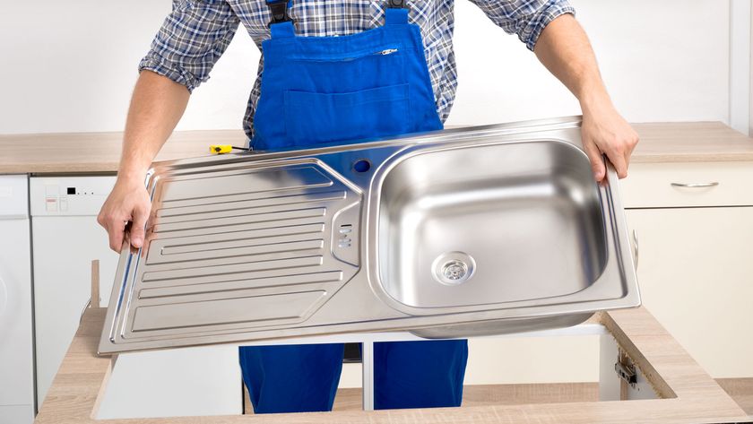 Man in blue overalls putting new kitchen sink into worktop cut out