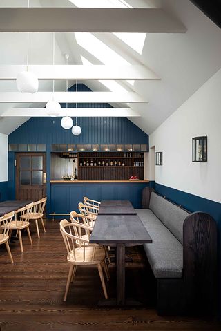 Interior of the Kinneuchar Inn, Fife, UK with blue and white painted walls, wooden furniture and bench with grey cushions