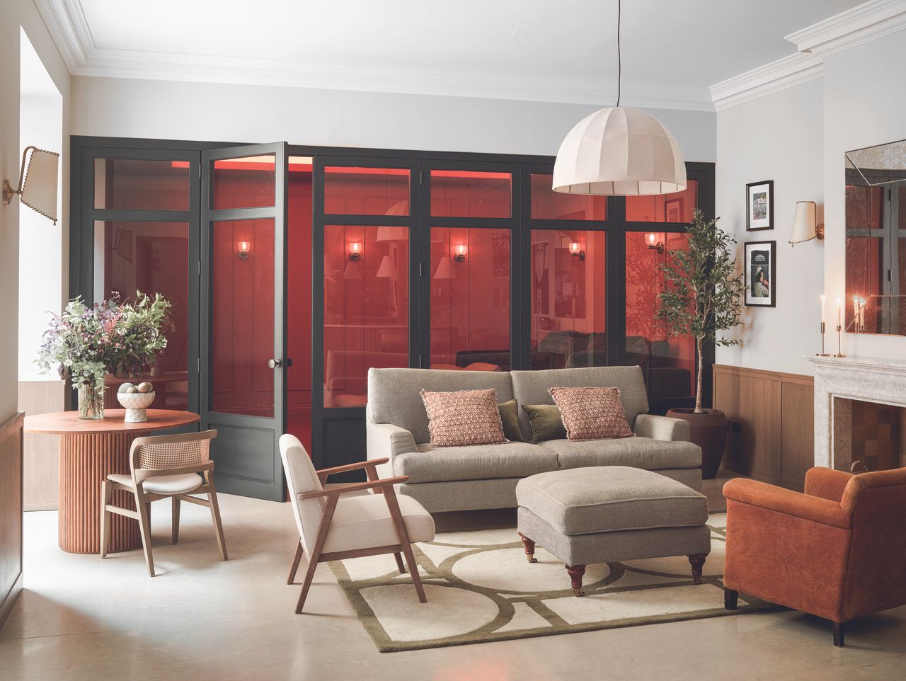 A two part living room separated by a glass wall, leading to a red living area