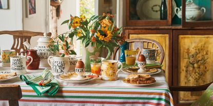 A breakfast table with boiled eggs and toast, decorated with a seclection of items from Emma Bridgewater including a vase with sunflowers 