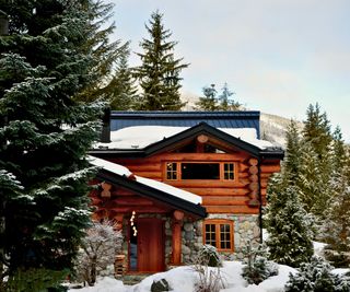 exterior view of log cabin in snow with fir trees