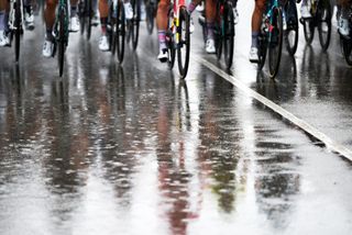 Reflection of peloton on rain-soaked roads